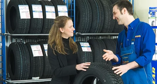 Man showing female customer a tyre from a selection