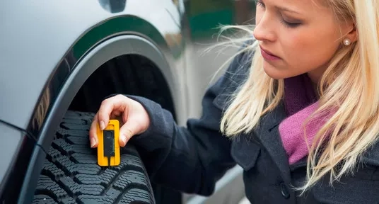 Woman checking tyre tread